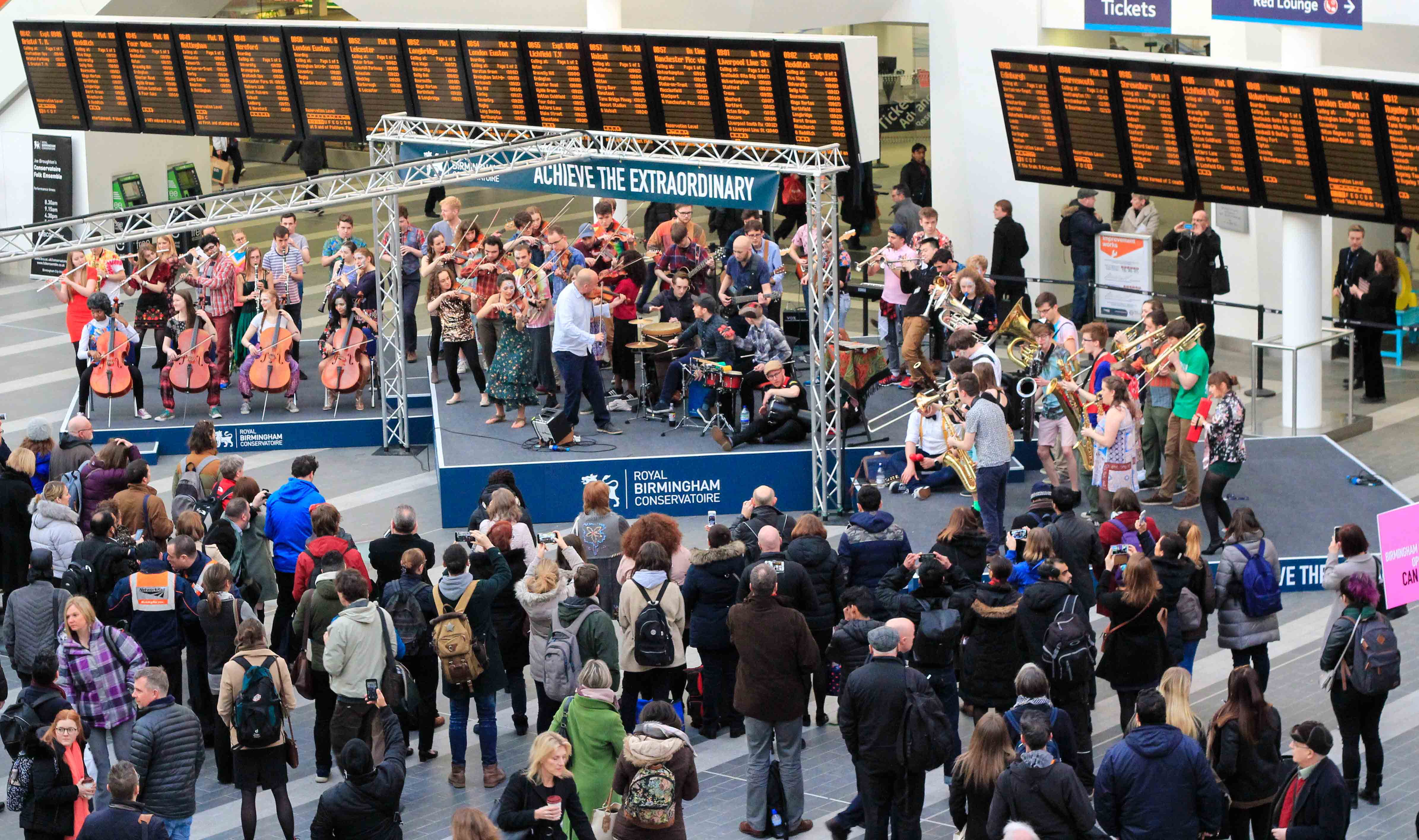 Fifteen horns, four cellos, five percussionists, five electric guitarists, plus fiddles, flutes, clarinets, double-bass, electric bass, euphonium, acoustic guitar, octave mandola, and a harp were part of the live music performance at New Street Station