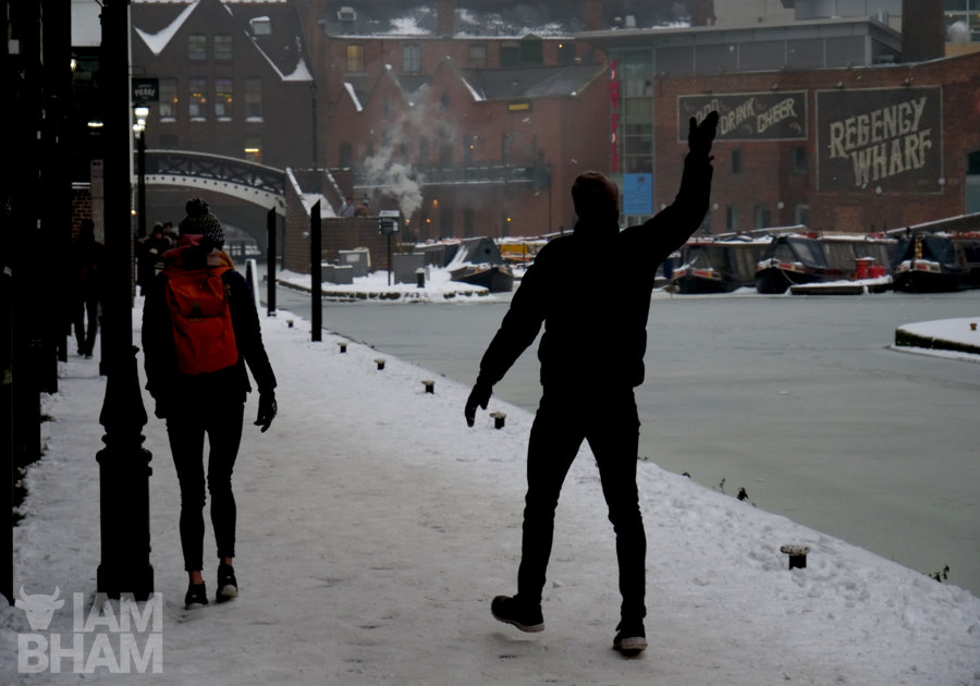 A man throws a snowball onto a frozen canal in Brindley Place in Birmingham