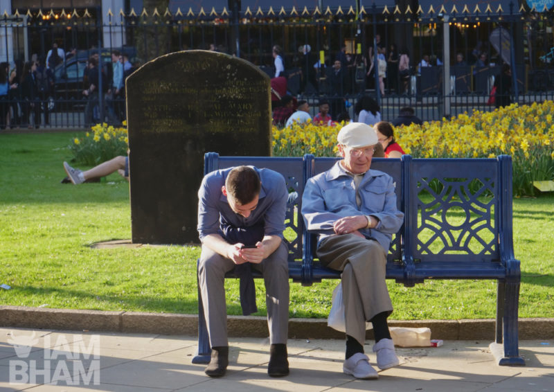 Two men relax on a bench in 'Pigeon Park' (Cathedral Square)