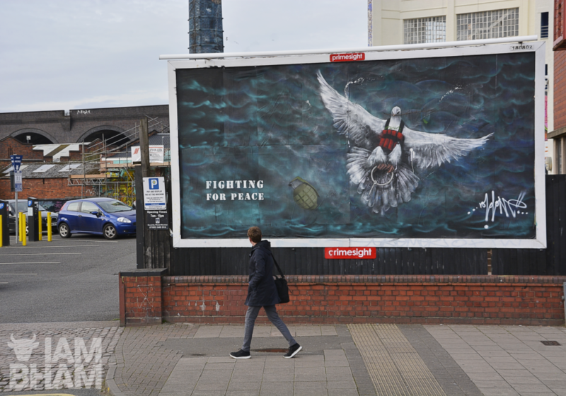 A member of the public walks past the political work of street art 'Death From A Dove - Fighting For Peace' by guerrilla artist Void One