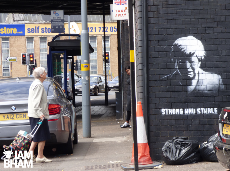 A pedestrian stops to look at the new Digbeth street art of Theresa May crying