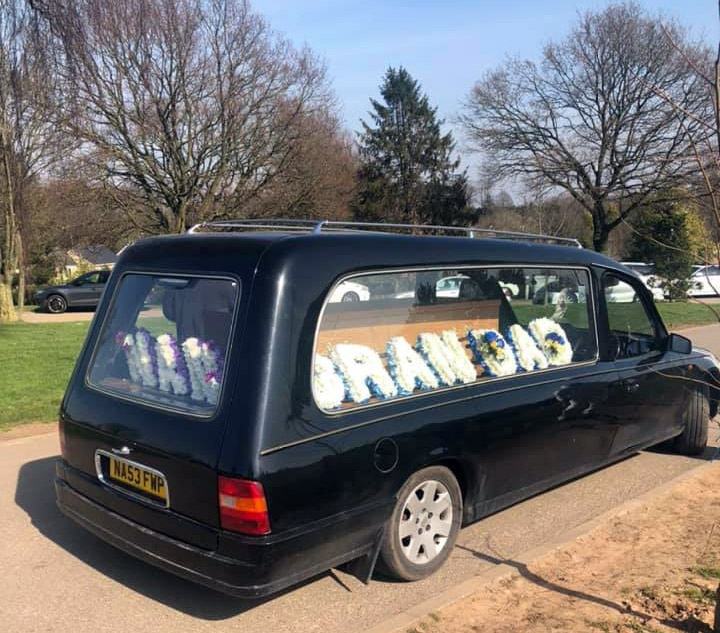 A hearse adorned with flowers carries Afsar Hussain's coffin in Birmingham 