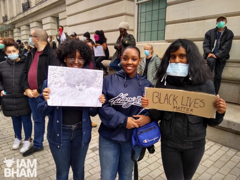 Three friends hold up banners at the Birmingham Black Lives Matter event