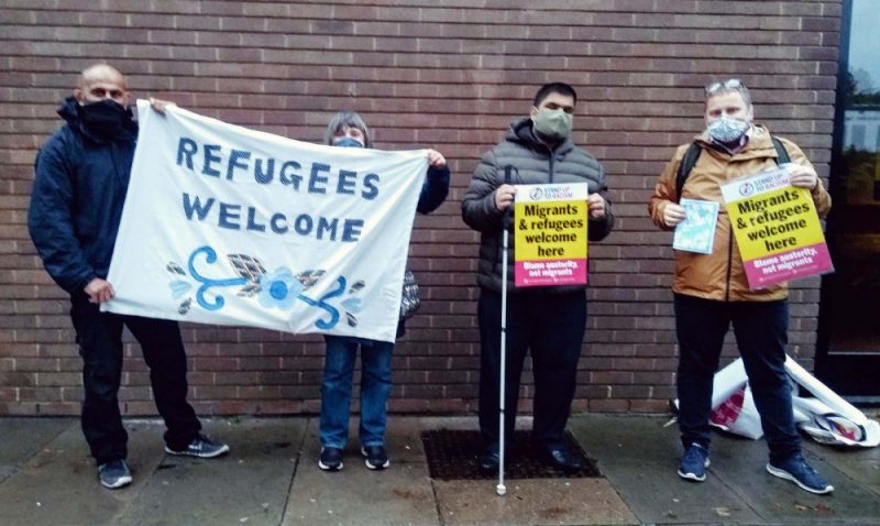 Teacher Doug Morgan (right) and Sandwell councillor Ahmad Bostan (second right) join a solidarity vigil welcoming refugees to the Midlands 