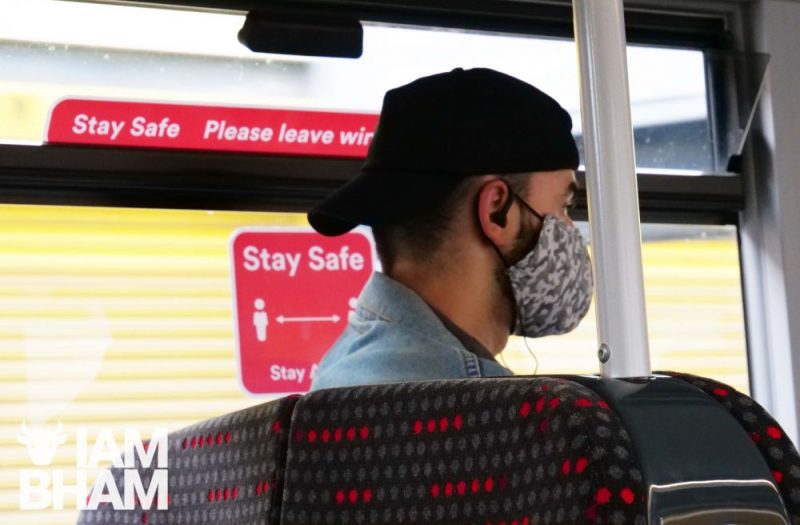 Young man in Birmingham on public transport wearing a face mask due to COVID coronavirus measures