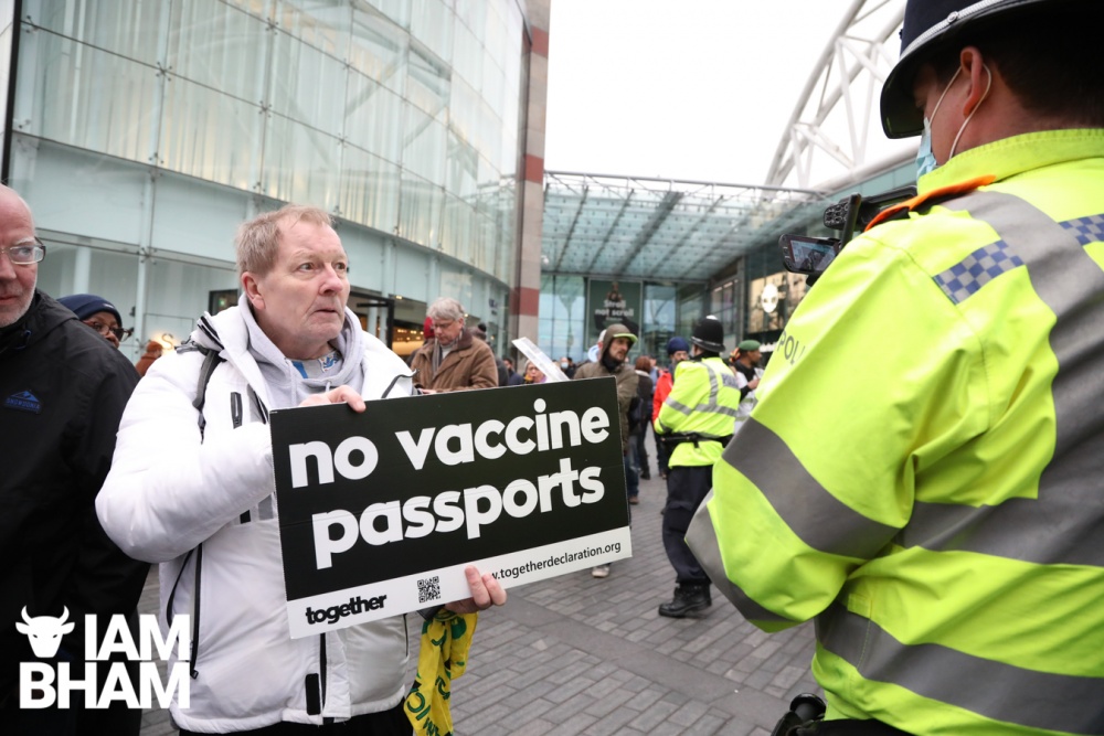An anti-vaccine passports protestor confronts a police officer in Birmingham 