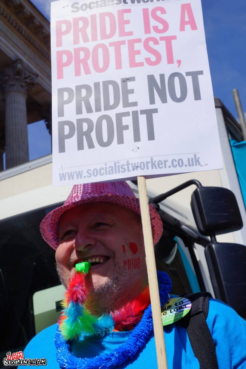 'Pride is a protest' placard and man with whistle