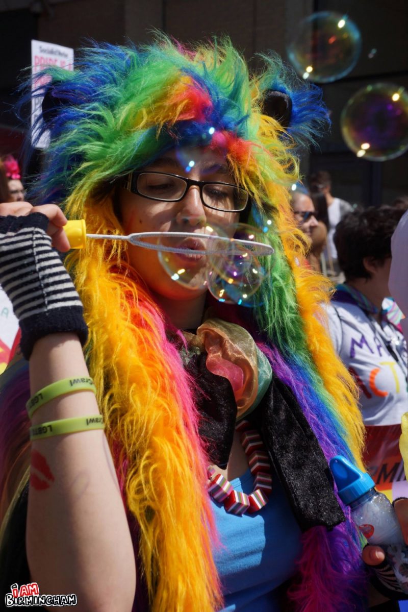 Blowing bubbles in rainbow costume at Pride 