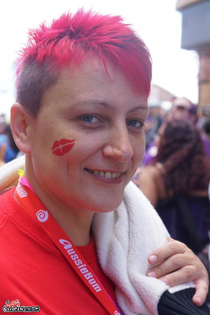 A person with red hair and red face paint in a heart shape during Birmingham Pride 