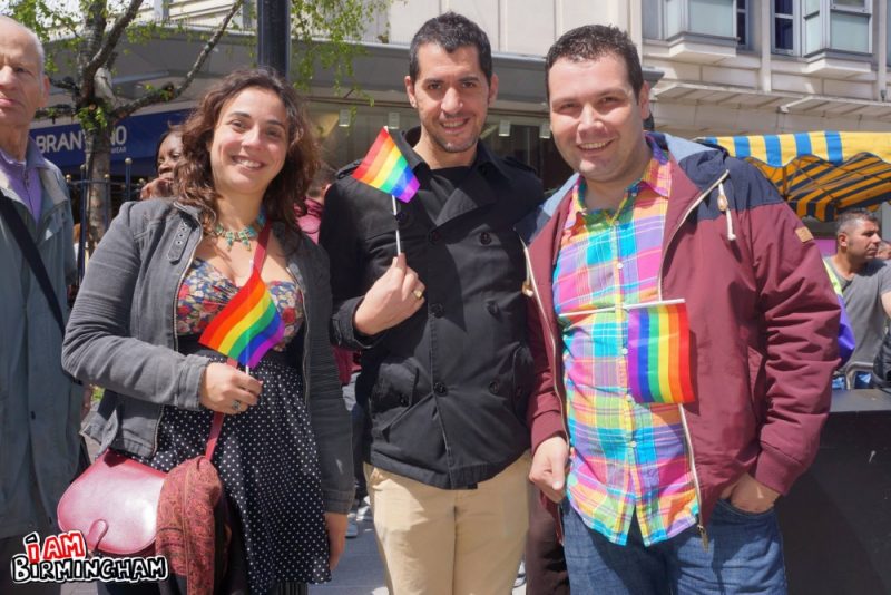 Pride revellers smile with rainbow flags