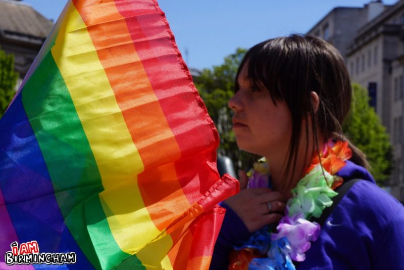 A Pride attendee with a large rainbow flag 