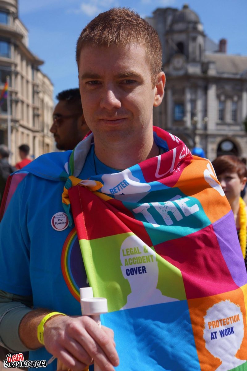 A man draped with a rainbow cape 