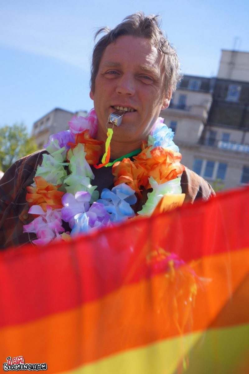 An attendee with a whistle and rainbow Pride flag