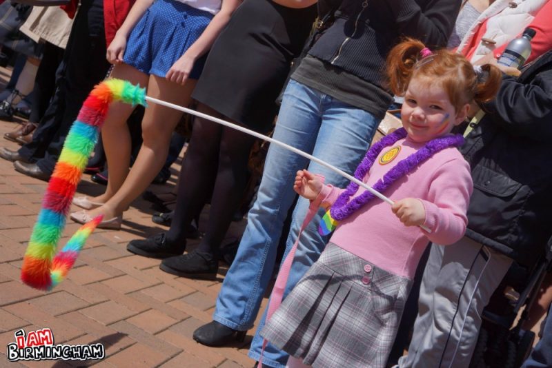 Young child holds up rainbow decoration 