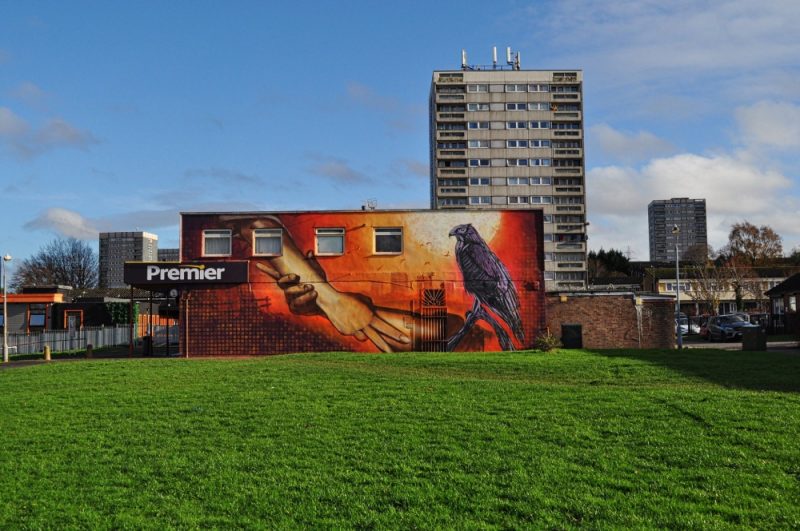 The finished mural glows in the afternoon sunlight as tower blocks loom in the background