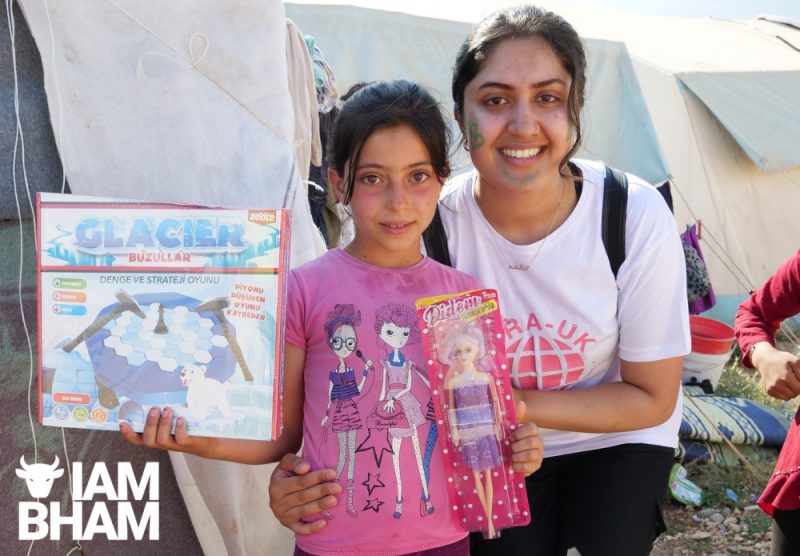 Aisha Nazir gives out toys to a young girl at a refugee camp in Osmaniya, Türkiye