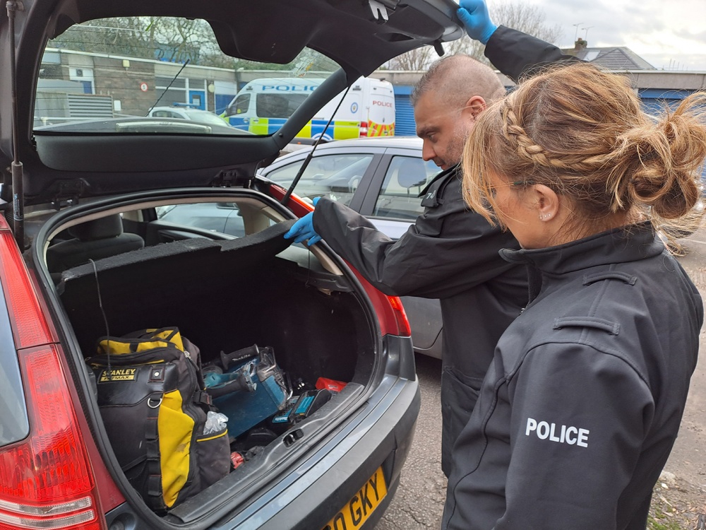 Coventry police officers inspecting car with stolen goods inside